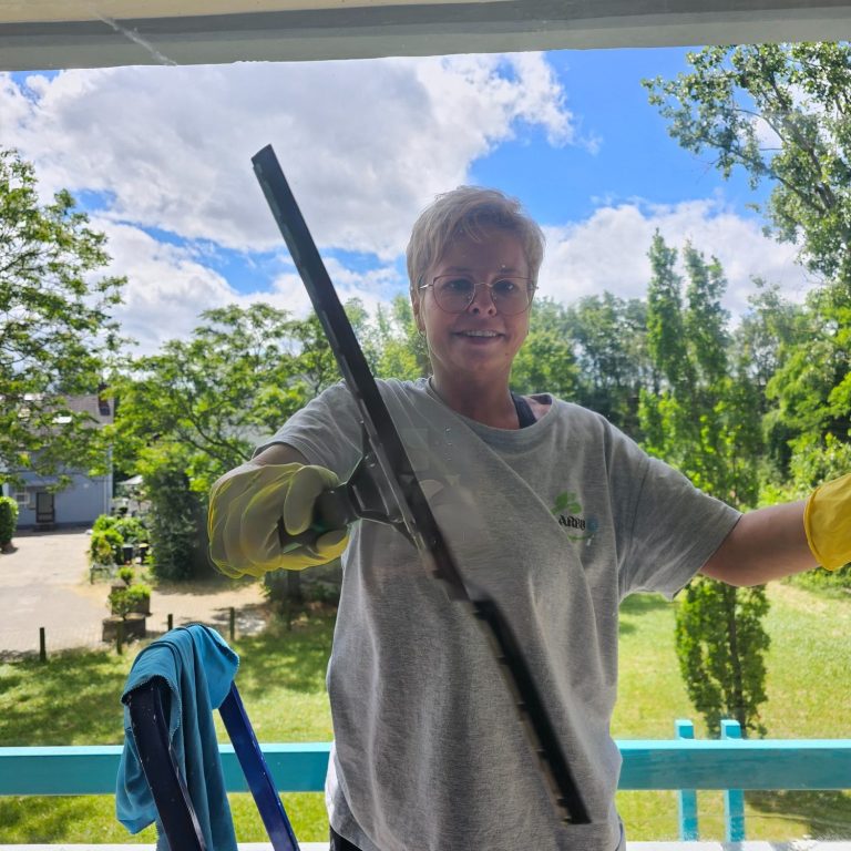 Mitarbeiterin bei der Fensterreinigung mit einem Lächeln – authentisch und freundlich